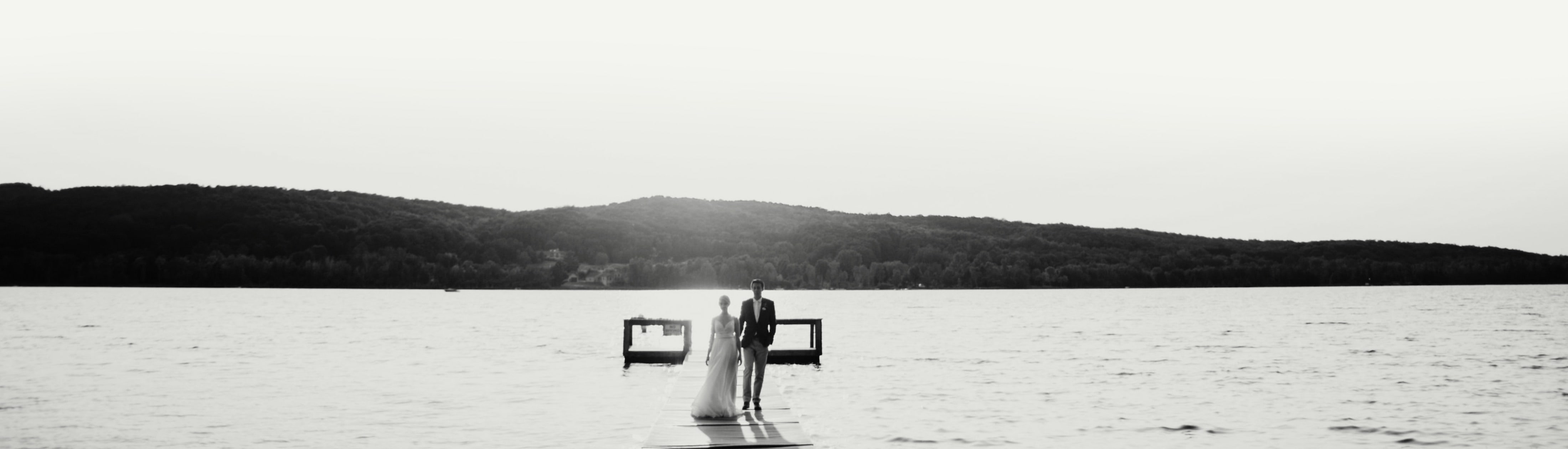 A bride and groom stand in front of Deer Lake